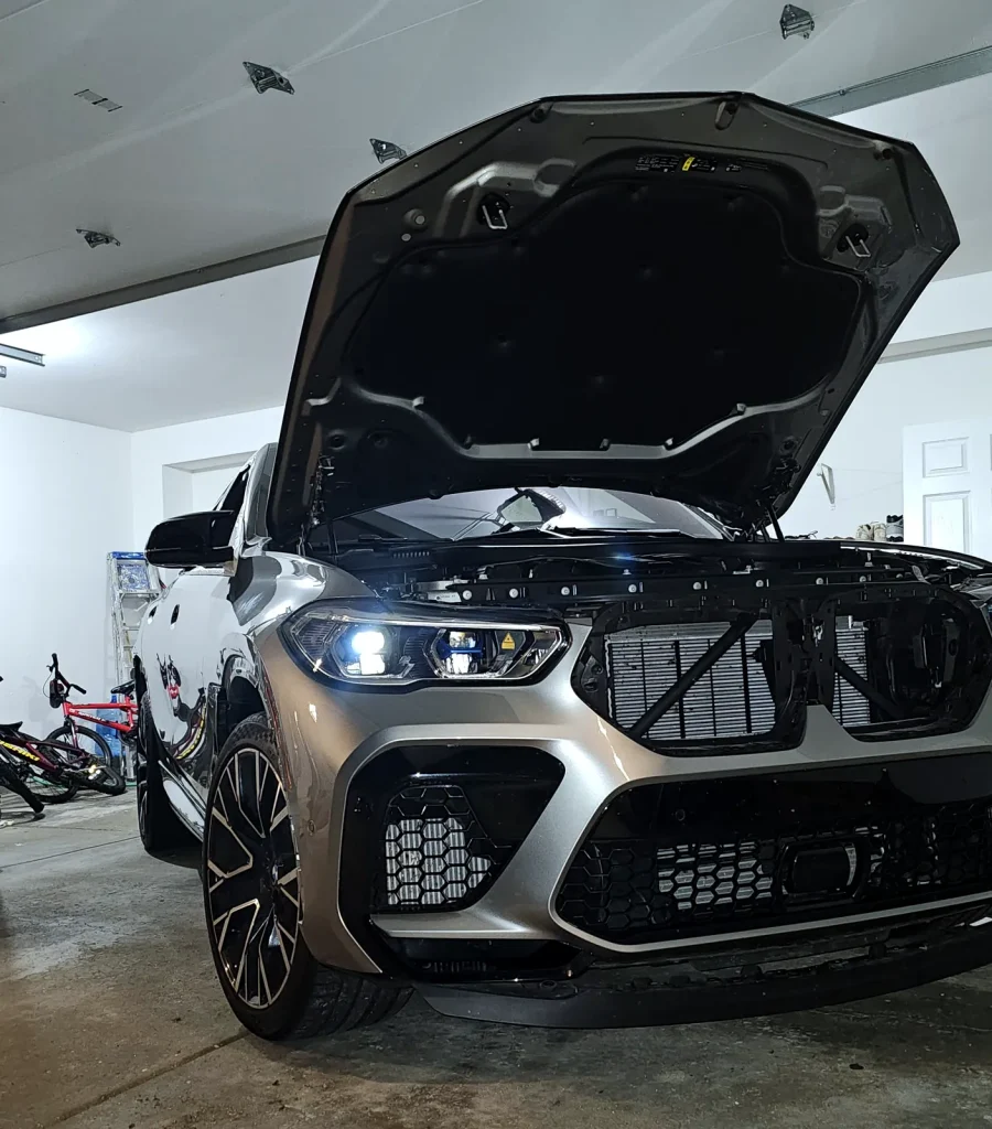 BMW X5 M with the hood open for engine diagnostics in the service bay