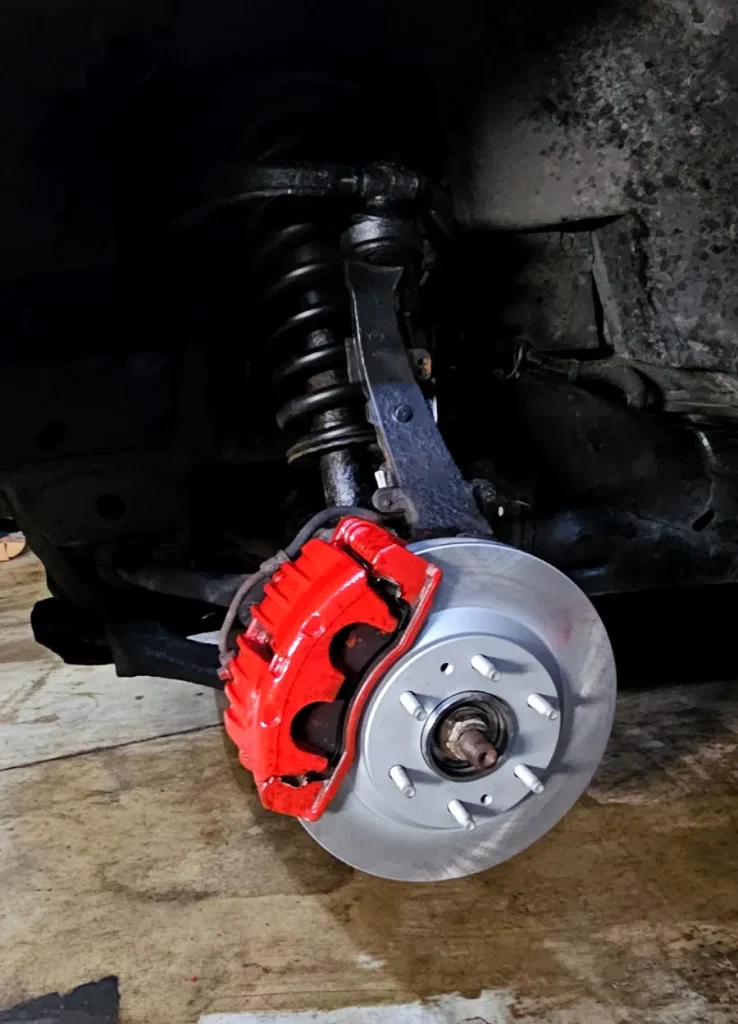 New brake rotor and red caliper during a brake service