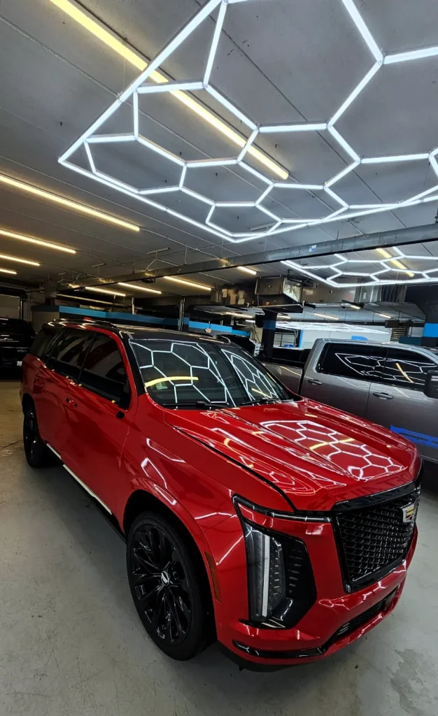 Cadillac Escalade with a gloss red finish under hexagon shop lights