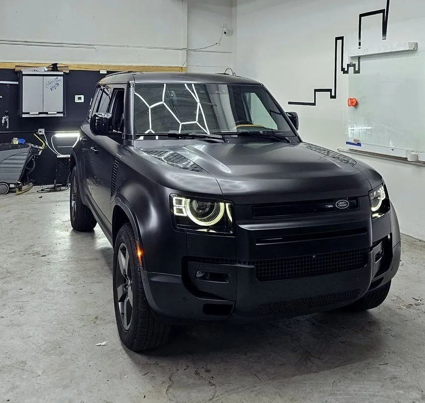 Land Rover Defender after a matte black wrap in the hexagon-lit bay