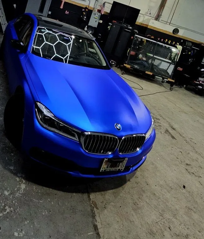 Matte blue wrap finish on a BMW under hexagon lights