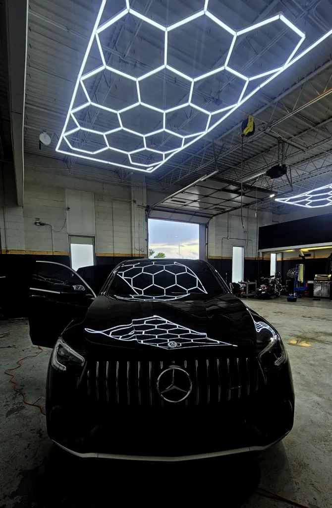 Black Mercedes-AMG GLE under the hexagon LED ceiling at MLUX Auto Service in La Grange, IL