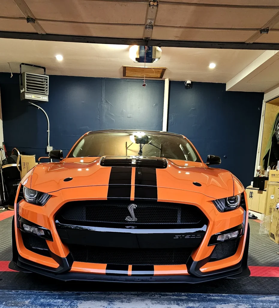 Orange Ford Shelby GT500 with black racing stripes, front view