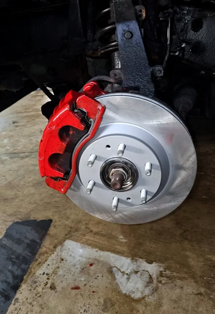 Red painted brake caliper and rotor after a brake service